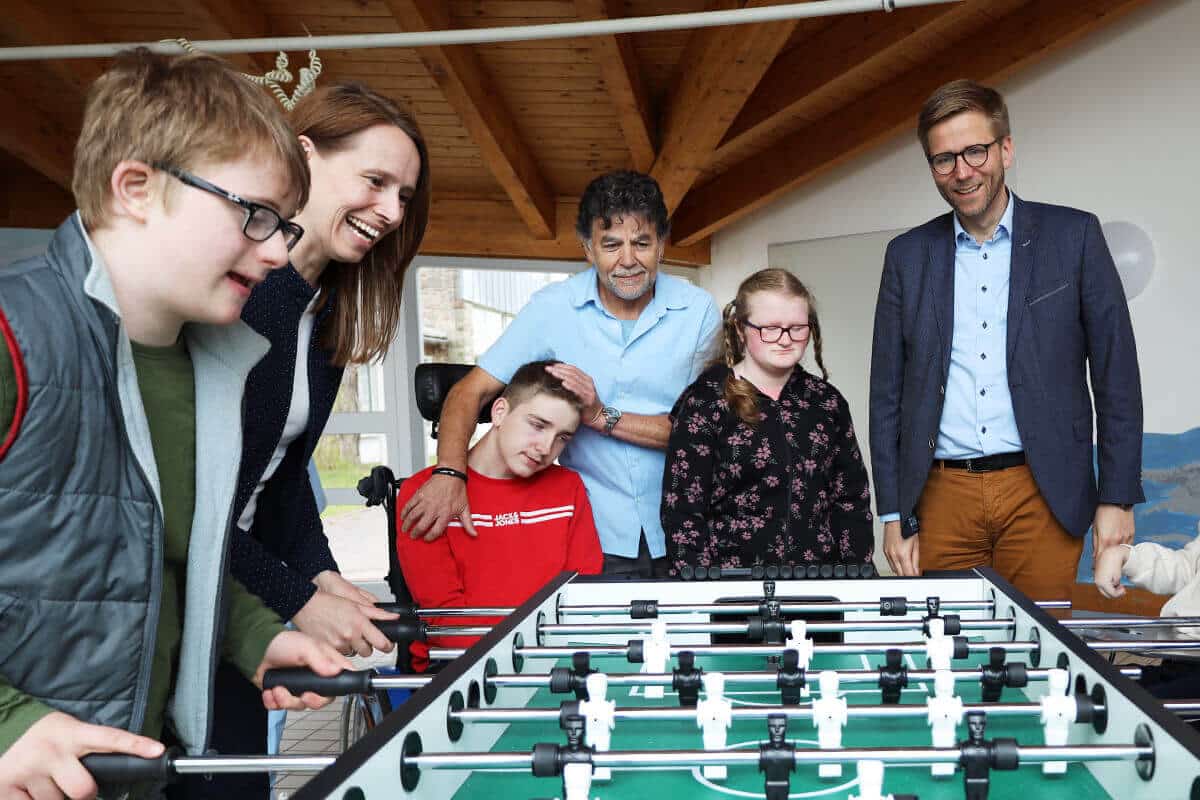 Gruppe von Erwachsenen und Jugendlichen spielt gemeinsam an einem Kicker