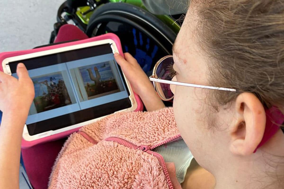 Person mit Brille hält ein Tablet mit zwei angezeigten Fotos in den Händen
